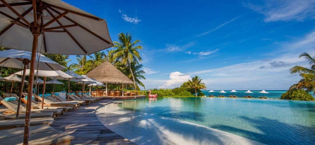 Poolside relaxing area with umbrellas and lounge chairs at a tropical resort.