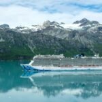 Cruise ship sailing through Glacier Bay with snow-capped mountains in the background.