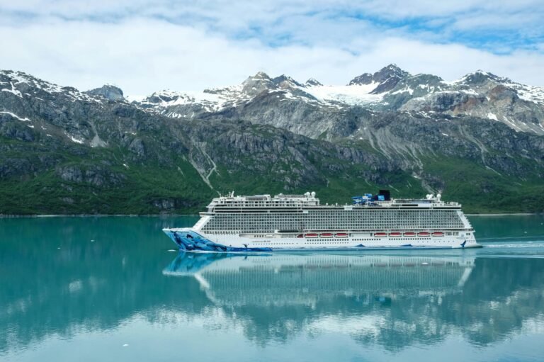 Cruise ship sailing through Glacier Bay with snow-capped mountains in the background.