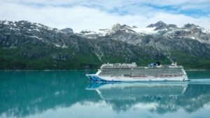 Cruise ship sailing through Glacier Bay with snow-capped mountains in the background.