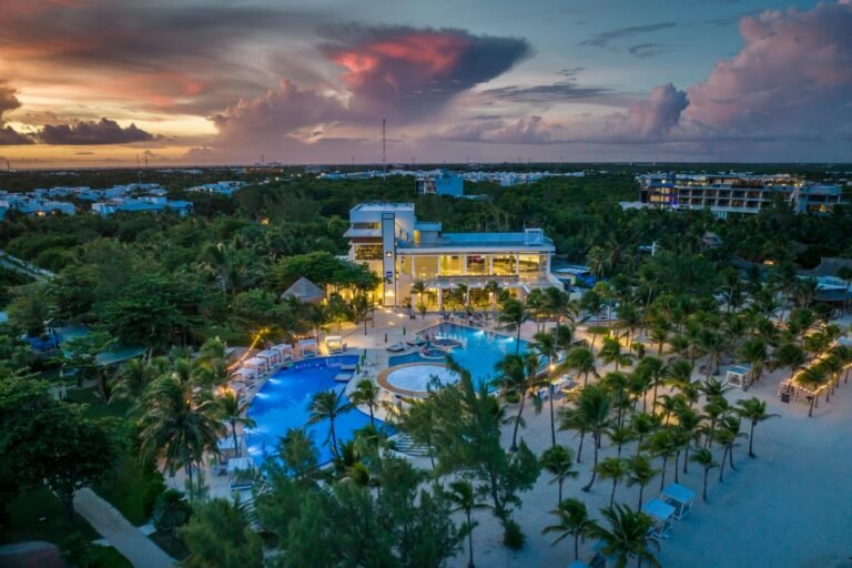 Beautiful tropical beach resort with pool and palm trees at sunset.