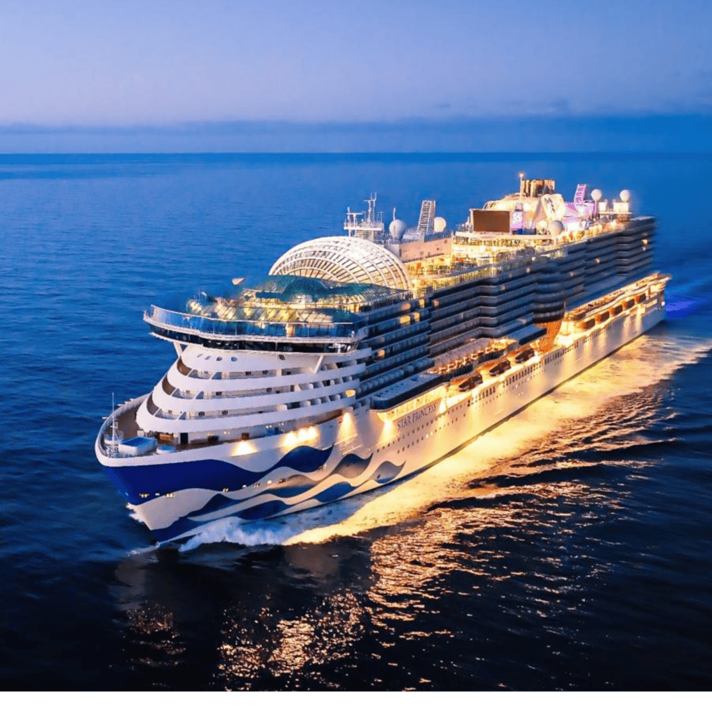 Luxury cruise ship sailing at night with illuminated decks and calm ocean waters.