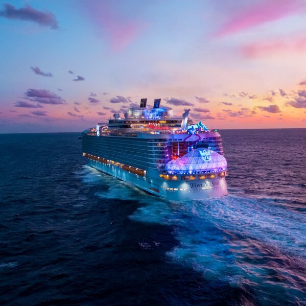 Luxury cruise ship sailing at sunset in the ocean.