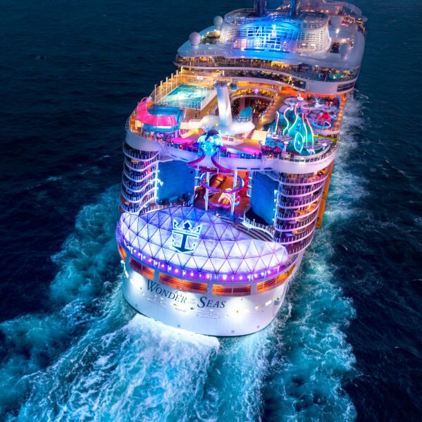 Night view of Wonder of the Seas cruise ship with colorful lights on the ocean.