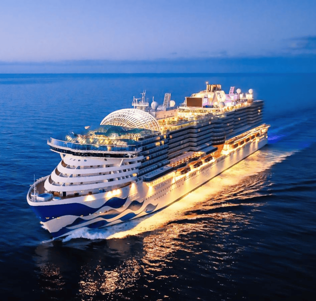 Elegant cruise ship with bright lights sailing on calm ocean waters at dusk.