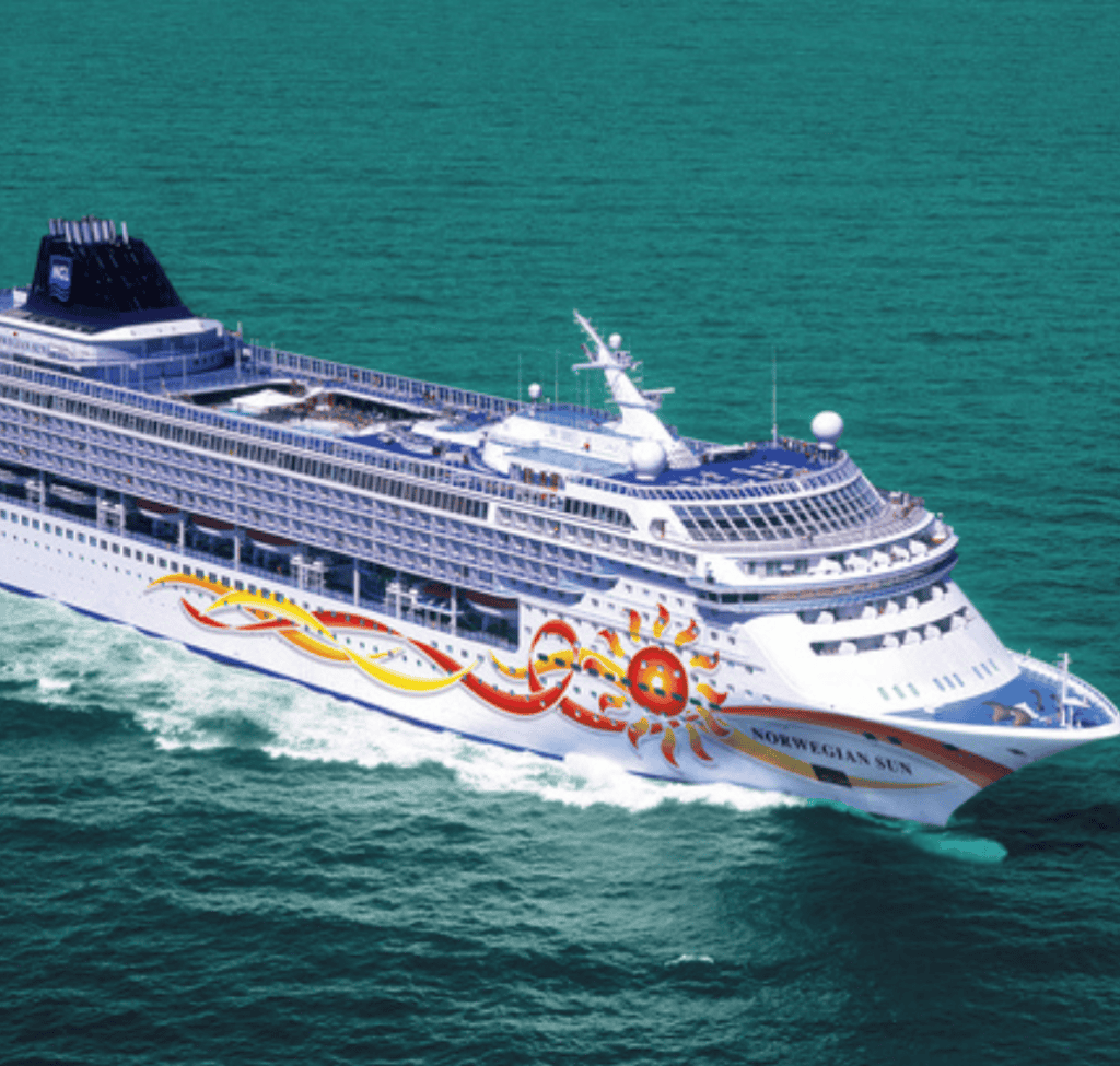 Luxury Norwegian Sun cruise ship sailing in open water, vibrant sun and wave design on hull.