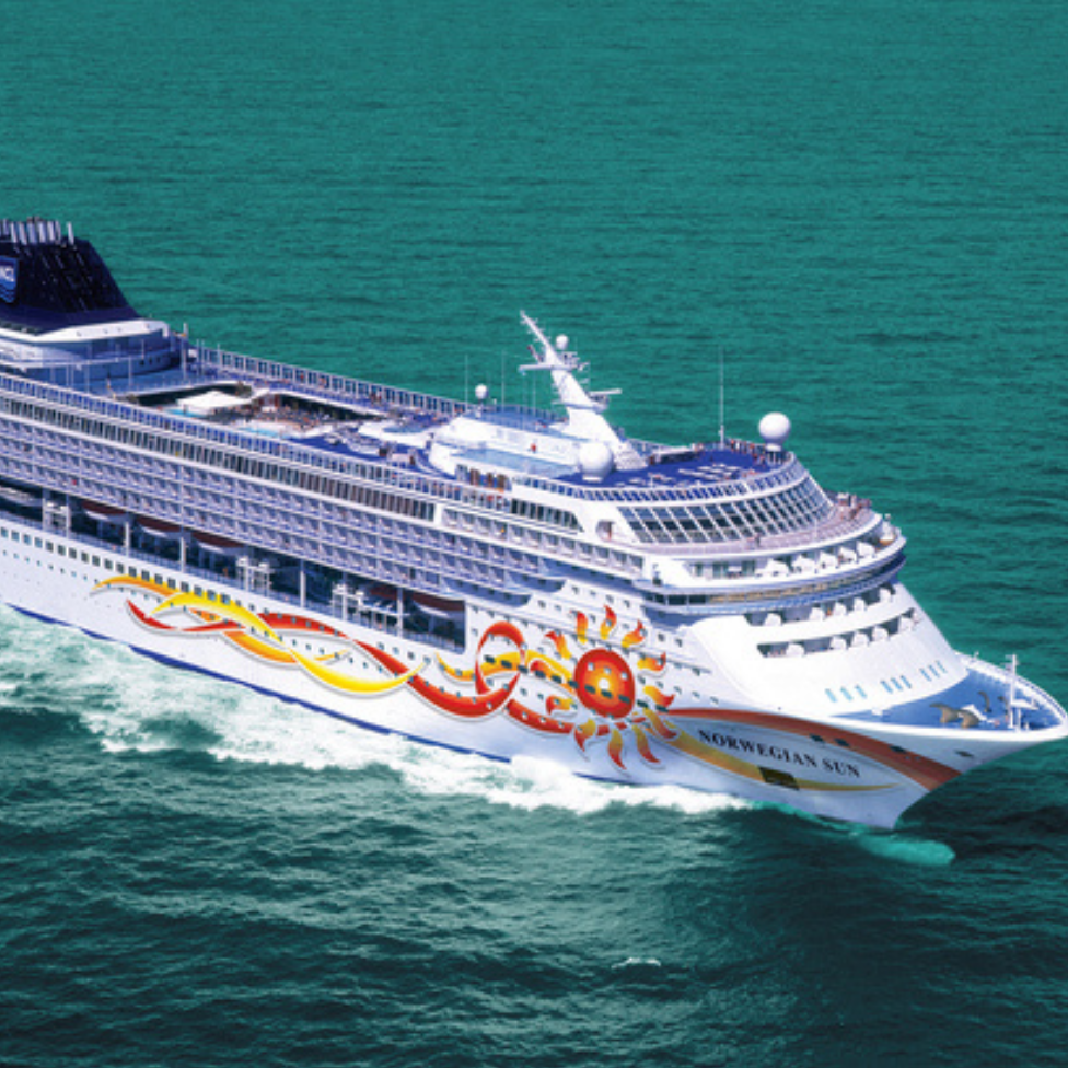 Luxury Norwegian Sun cruise ship sailing in open water, vibrant sun and wave design on hull.