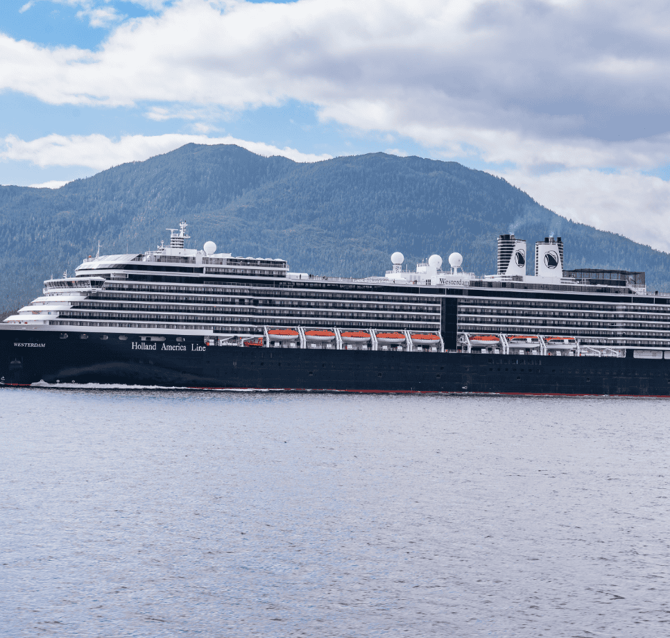 Luxury cruise ship sailing through calm waters with mountainous backdrop.
