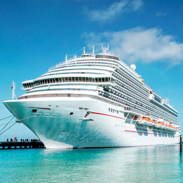 Large luxury cruise ship docked at the port under a blue sky.
