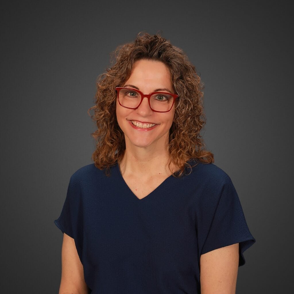 Portrait of Tracy from NextStop Travel wearing red glasses and a navy top.